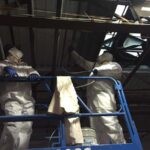 Metal ceiling being painted black by two painters in a scissor lift using a paint sprayer