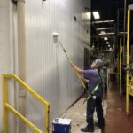 Main painting metal wall white using a roller and a commercial food processing facility
