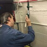 Painter using a brush to paint a pipe green