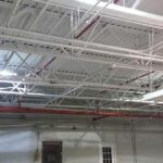Freshly painted white warehouse ceiling with red sprinkler pipes