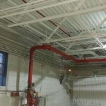 Freshly painted production facility ceiling with white paint and freshly painted red sprinkler pipes