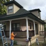 Front porch floor being painted with a roller on a small residential home