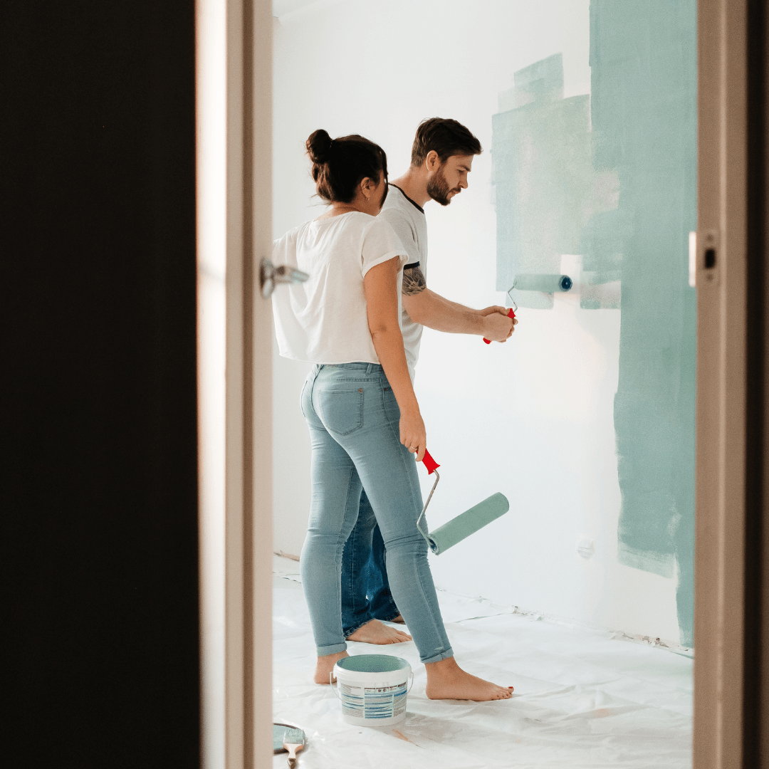 two people painting a wall blue