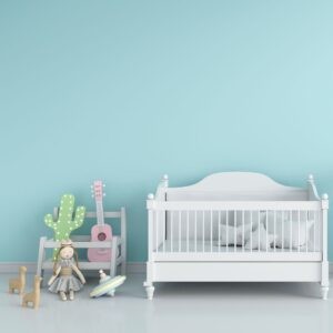 Crib and decorations up against a light blue wall. 
