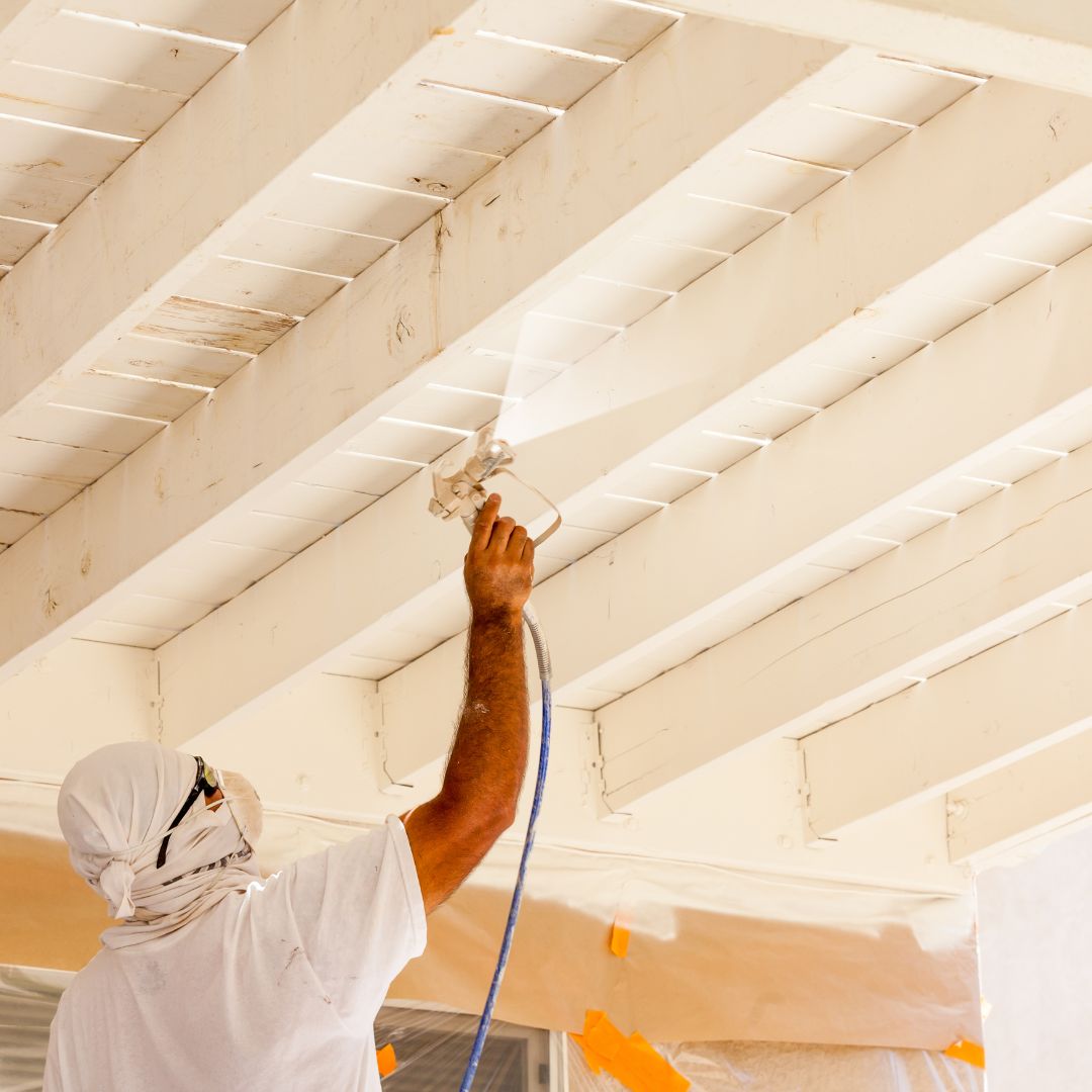 painter spraying paint on ceiling