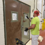 painter rolling paint onto a steel door in a factory