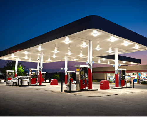 gas station painting The exterior pavilion of a gas station. The pylons are painted red and white and the parking bollards are painted black. In the background a convenience store with tan and red stucco siding can be seen.